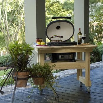 Charcoal Primo Grill on a movable wooden table on the porch