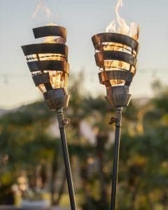 The Outdoor Plus Spiral Fire Torch is a handcrafted lighting fixture made in the USA, designed to serve as both functional art and a premium flame feature for patios, pool areas, or landscapes. Constructed from high-grade 304 stainless steel, it is built to withstand extreme temperatures and natural elements while resisting rust and corrosion. This modern torch operates at a maximum heat output of 20,000 BTU/hr and is compatible with either natural gas or liquid propane. It utilizes a simple match-lit ignition system and is available with two base options: the "Original TOP" base, which features a needle valve for precise flame adjustment and fits standard 2.5-inch posts, and the "TOP-LITE" base, designed for quick installation onto any 0.5-inch gas pipe.